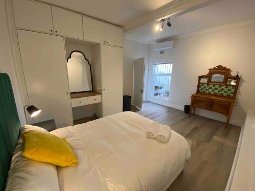 Un dormitorio con una gran cama blanca y una mesa en Auret Street Garden Cottage en Paarl