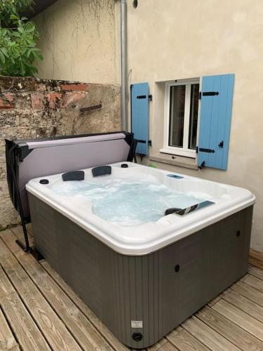 une grande baignoire assise sur une terrasse en bois dans l'établissement La petite maison de Justin - Jacuzzi privatif, à Bagnères-de-Bigorre