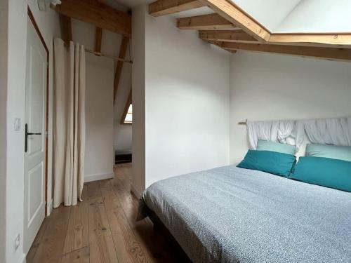a bedroom with a bed with blue pillows at La petite maison de Justin - Jacuzzi privatif in Bagnères-de-Bigorre