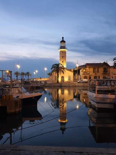 a lighthouse in a harbor with boats in the water at jolies studios avec piscines et parking privé 800m de la plage le grau du roi in Le Grau-du-Roi
