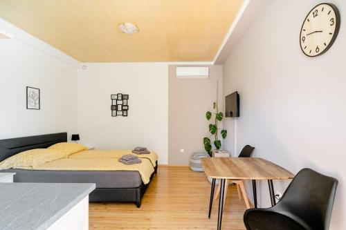 um quarto com uma cama, uma mesa e um relógio em Airport Garden Room em Cilipi