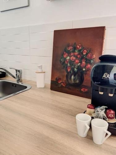 un comptoir de cuisine avec des tasses et un tableau de fleurs dans l'établissement Le Charles - Campagne chic, à Jaux