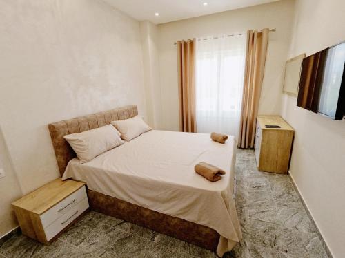 a small bedroom with a bed and a television at Matteo's Apartments in Velipojë