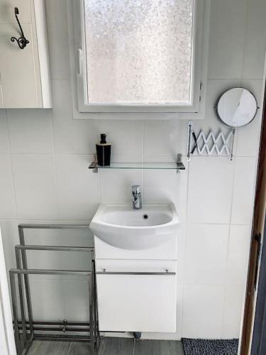 une salle de bain blanche avec un lavabo et une fenêtre dans l'établissement Le Charles - Campagne chic, à Jaux