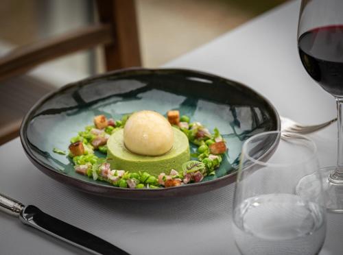 a plate of food on a table next to a glass of wine at Hôtel de la Plage in Plonévez-Porzay