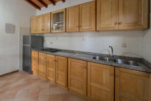 uma cozinha com armários de madeira e um frigorífico de aço inoxidável em Residence Baia delle Grazie em Casa Morcone