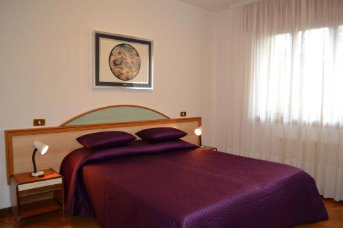 1 dormitorio con cama morada y ventana en Villa Rita Luciana, en Lignano Sabbiadoro