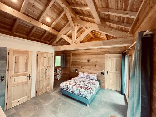 una camera con letto in una stanza con soffitti in legno di Gîte Chalet La Vie Sauvage a Prats-Haut