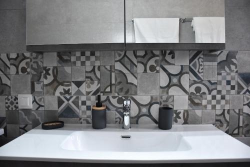 a white sink in a bathroom with a tile wall at Salt and petals in Samothraki