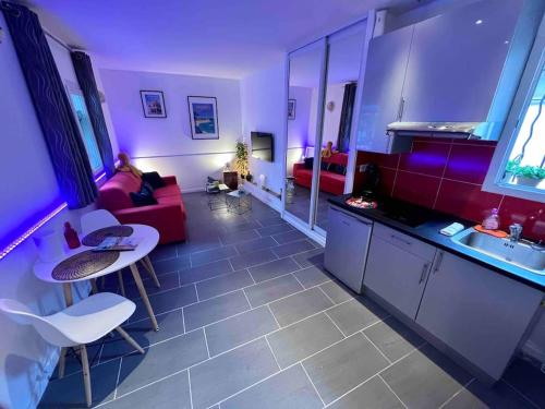 un salon avec un canapé rouge et une cuisine dans l'établissement Au petit QG: Apt cosy pour 2 Prs, 200m des plages, à Antibes