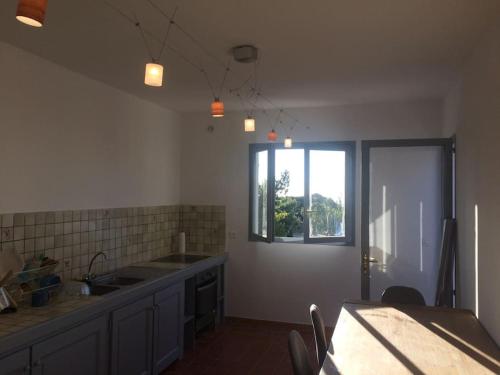 une cuisine avec un évier, une table et une fenêtre dans l'établissement Fraîcheur et calme en montagne 30 mn de la mer, à Porto-Vecchio