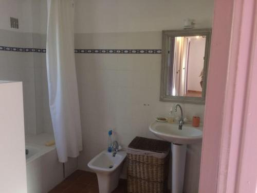 une salle de bain blanche avec un lavabo et un miroir dans l'établissement Fraîcheur et calme en montagne 30 mn de la mer, à Porto-Vecchio