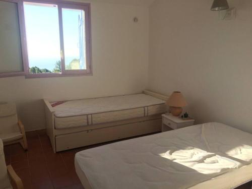une chambre avec deux lits et une fenêtre dans l'établissement Fraîcheur et calme en montagne 30 mn de la mer, à Porto-Vecchio