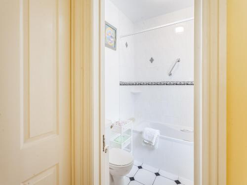 a white bathroom with a toilet and a bath tub at Robin Cottage in Temple Combe