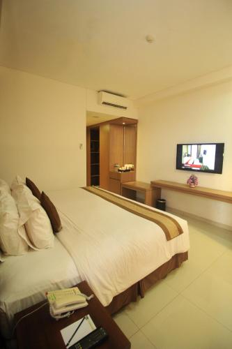 a hotel room with a bed and a flat screen tv at Hotel on The Rock in Kupang