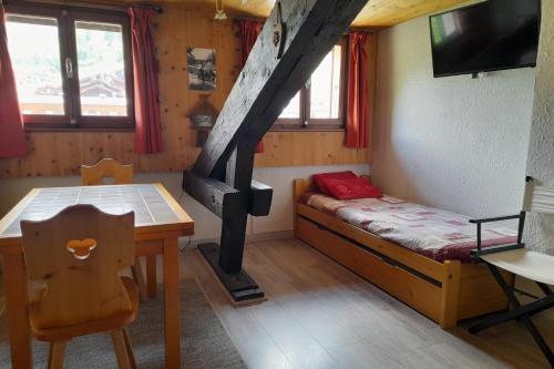 Habitación pequeña con cama, mesa y fogones. en Studio in the center of the village en La Clusaz