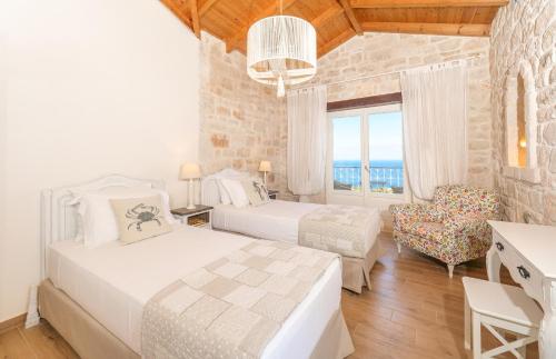 a bedroom with two beds and a chair and a window at The Yiameli Collection - Levandi in Skinária