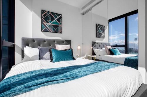 een slaapkamer met 2 bedden en een groot raam bij Stunning City Views 2 bed 2 bath- Ur Urban Oasis！ in Melbourne