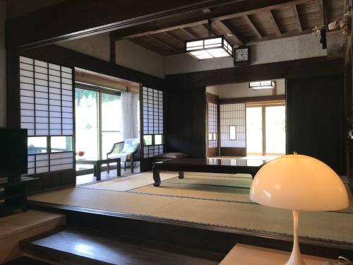 uma sala de estar com uma mesa num quarto com janelas em ビラ里山双林 em Inashiki