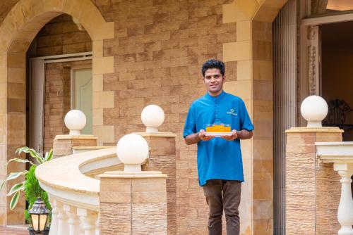 a man standing in front of a building holding a box at SaffronStays Grandiosa - 4 BDR pet-friendly, pool villa Khandala in Khandala