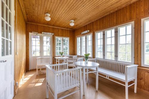 una stanza con panche e tavoli bianchi e finestre di Hotelli Siuntio a Sjundeå
