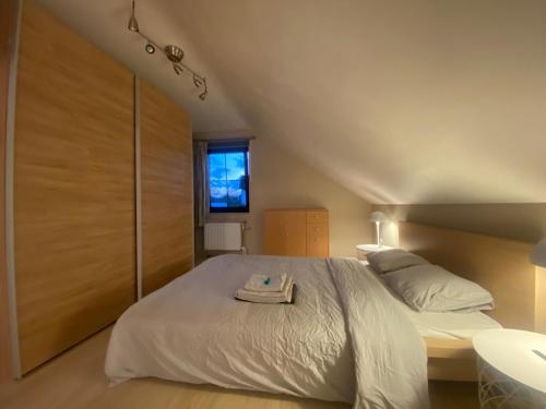 Un dormitorio con una gran cama blanca y una ventana en Hébergement à 20 min à pied du circuit Spa-Francorchamps, en Malmedy