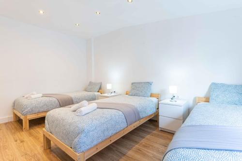 um quarto com três camas com lençóis azuis e brancos em Reial 4 Tarragona em Tarragona
