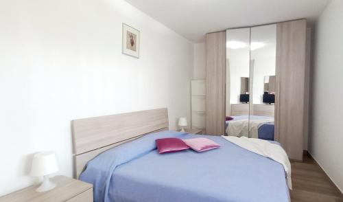 een slaapkamer met een blauw bed met 2 roze kussens bij RosMarino_Appartamento Fronte Mare in Roseto degli Abruzzi