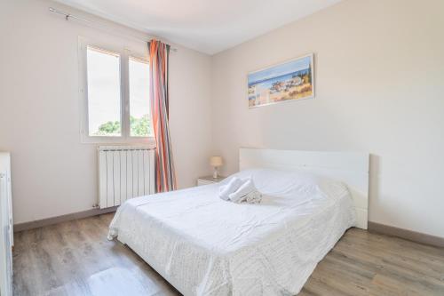 ein weißes Schlafzimmer mit einem Bett und einem Fenster in der Unterkunft La Calanque in Marseille