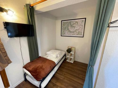 Cette petite chambre comprend un lit et une télévision à écran plat. dans l'établissement Studio cosy aux pieds des pistes, à Valfréjus