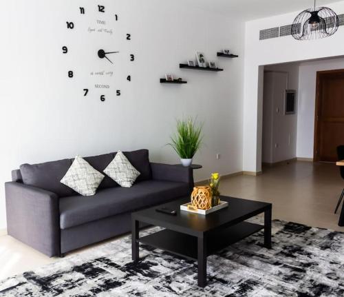 a living room with a couch and a clock on the wall at Supurb 2 Bed Apt Beach Front (City View) in Abu Dhabi