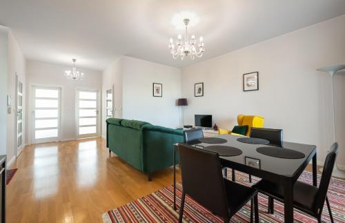 a living room with a table and a green couch at Mokotów 2-Bedroom Premium Apartment in Warsaw