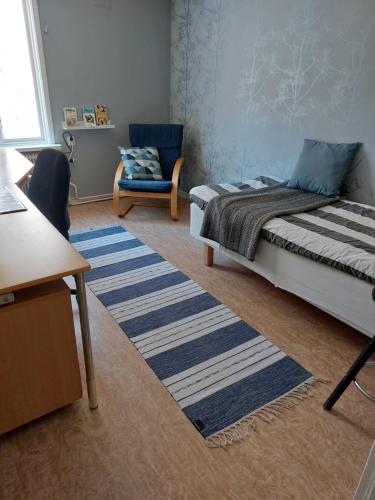 1 dormitorio con 1 cama, 1 silla y 1 alfombra en Flora Dekor gästgård, Lenagården en Alingsås