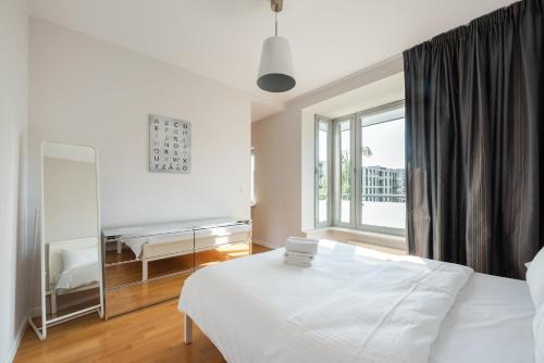 a white bedroom with a bed and a mirror at Mokotów 2-Bedroom Premium Apartment in Warsaw