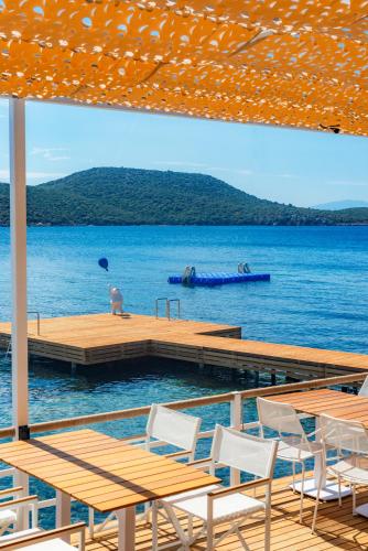 a dock with tables and chairs on a body of water at Doria Hotel Bodrum-City Center in Bitez