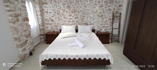 una camera da letto con letto, lenzuola e cuscini bianchi di Xenonas "Alexandra's Coffee House" a Volímai