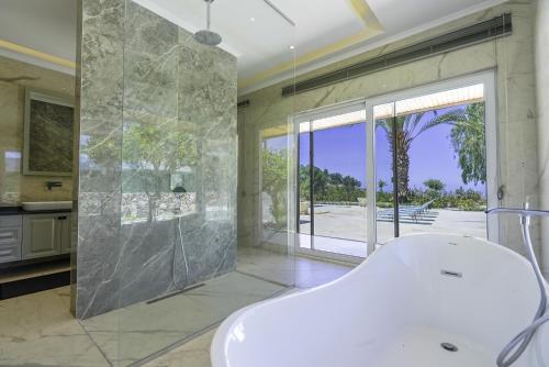 a bathroom with a white tub and a large window at Sea View Terrace Big Villa w Pool 5 min to Beach in Seki