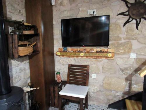 een kamer met een stenen muur, een tv en een stoel bij La alegria de las cuevas in Rus