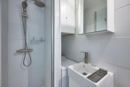a white bathroom with a sink and a shower at Un Balcon sur la Mer - Appt à 30m de la plage in Saint-Aubin-sur-Mer