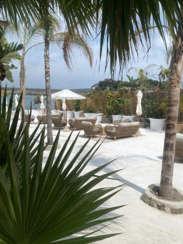 a patio with lounge chairs and palm trees and the ocean at Pagoda Lifestyle Hotel in Ischia