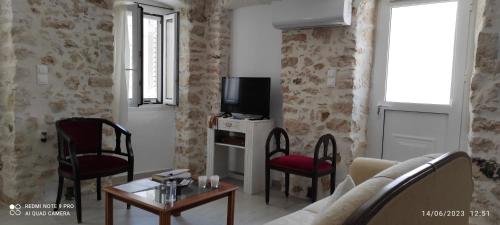 a living room with a couch and chairs and a tv at Xenonas "Alexandra's Coffee House" in Volímai