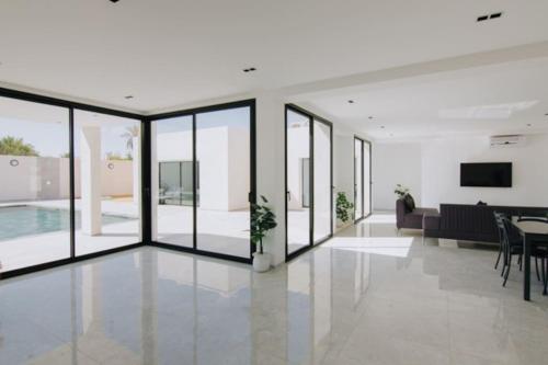 a living room with glass doors and a dining room at Villa Bali Djerba sans vis a vis in Midoun