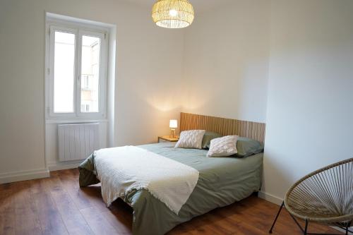a bedroom with a bed and a window and a chair at Appart Lumineux 150 m de la Gare in Bourg-en-Bresse