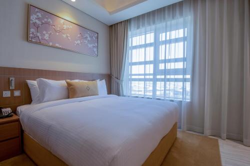 a bedroom with a large bed and a large window at Jood Hotel Apartments in Dubai