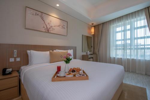 a bedroom with a bed with a tray of food on it at Jood Hotel Apartments in Dubai