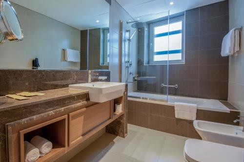 a bathroom with a sink and a shower and a tub at Jood Hotel Apartments in Dubai
