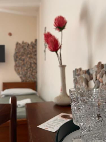 un tavolo con un vaso con fiori rossi di Sole Mare B&B a Giardini Naxos