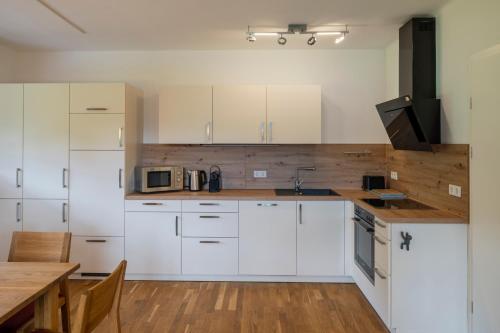 a kitchen with white cabinets and a wooden table at mivida - Apartment zum Arber in Hohentauern