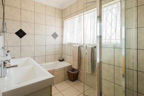 a bathroom with a sink and a tub and a shower at Golfer's Lodge in Edenvale