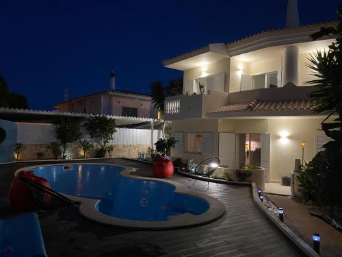 a swimming pool in front of a house at night at Vila Luisa Anabela Piscine et Jacuzzi only family in Albufeira
